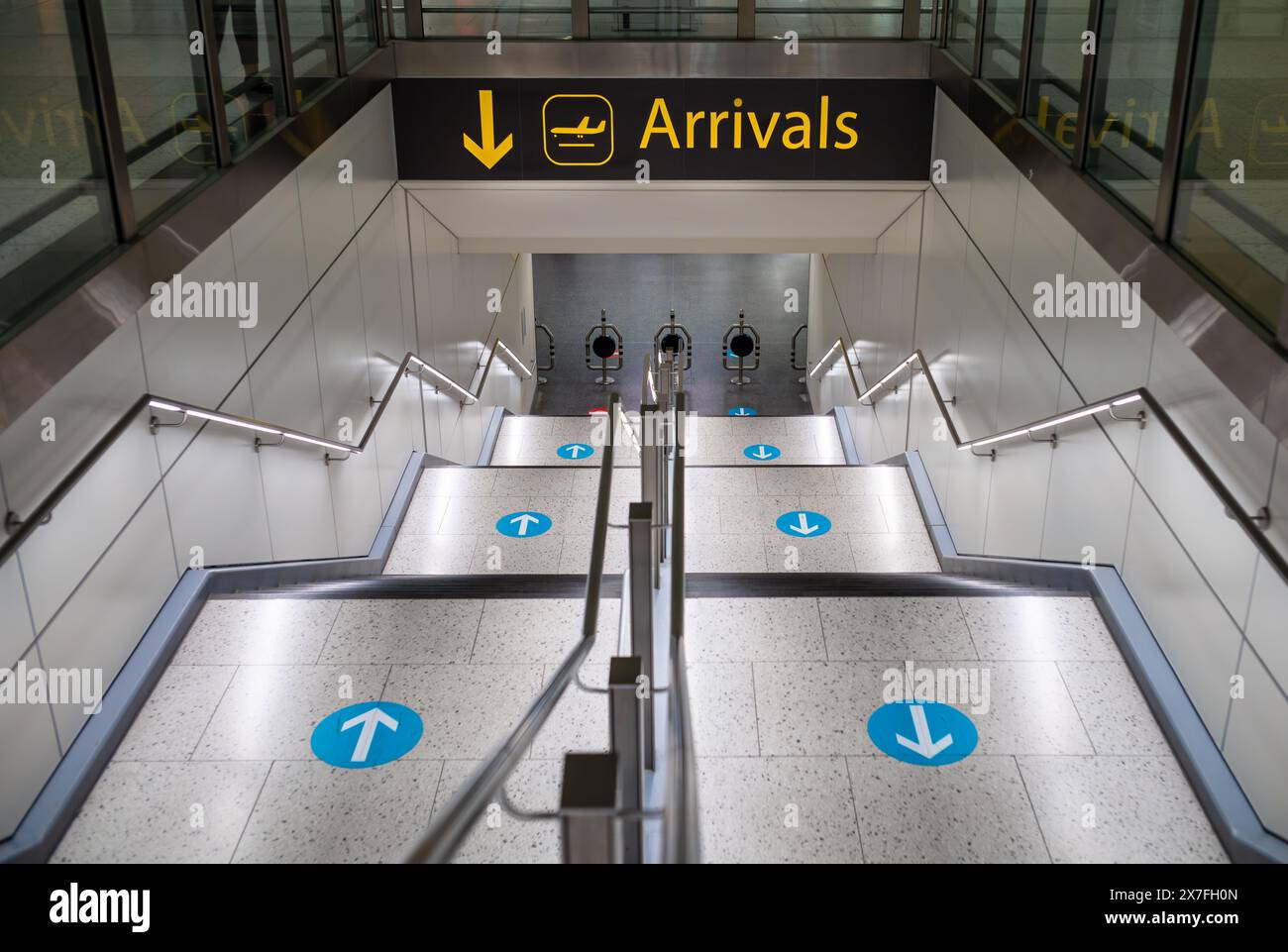 A staircase with blue direction arrows leading to Arrivals at London