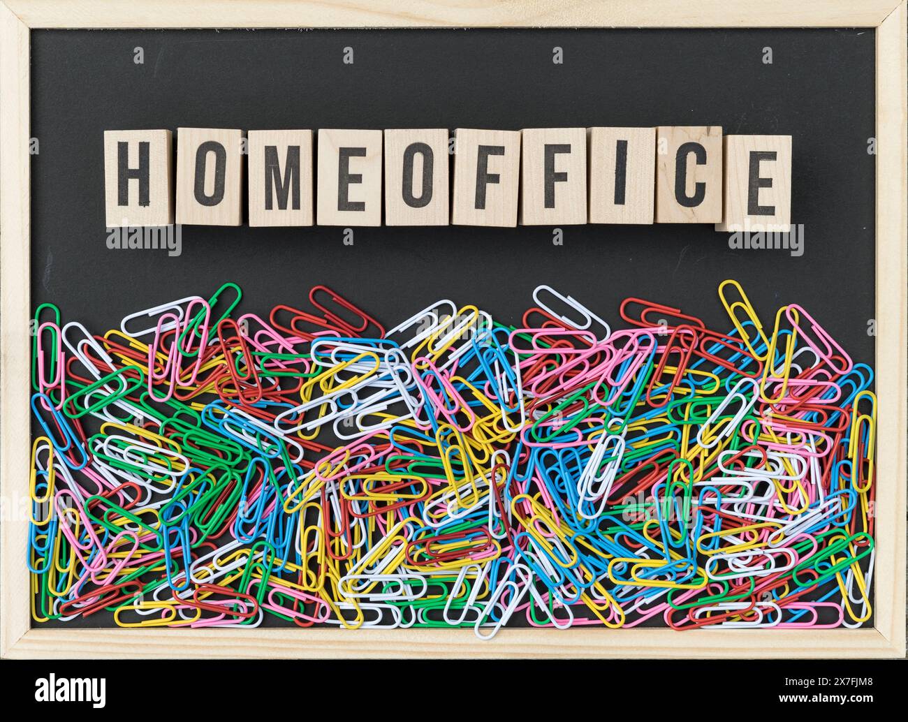 Black Background with colorful paper clips and wooden cubes with the text: Homeoffice Stock Photo