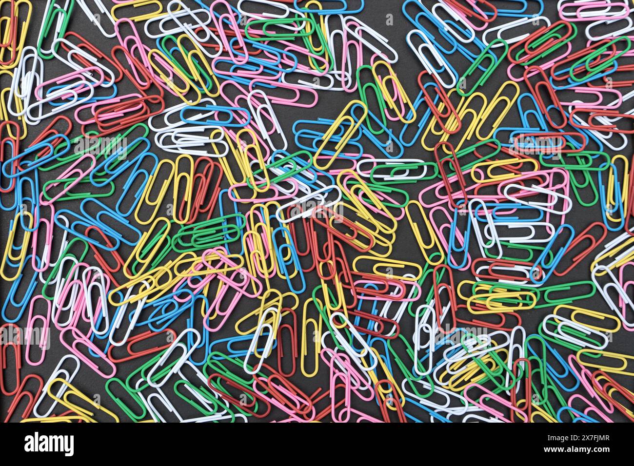 View from above of a black background with colorful paper clips Stock Photo