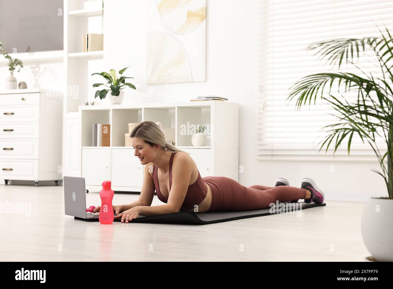 Online fitness trainer. Woman watching tutorial on laptop at home Stock Photo
