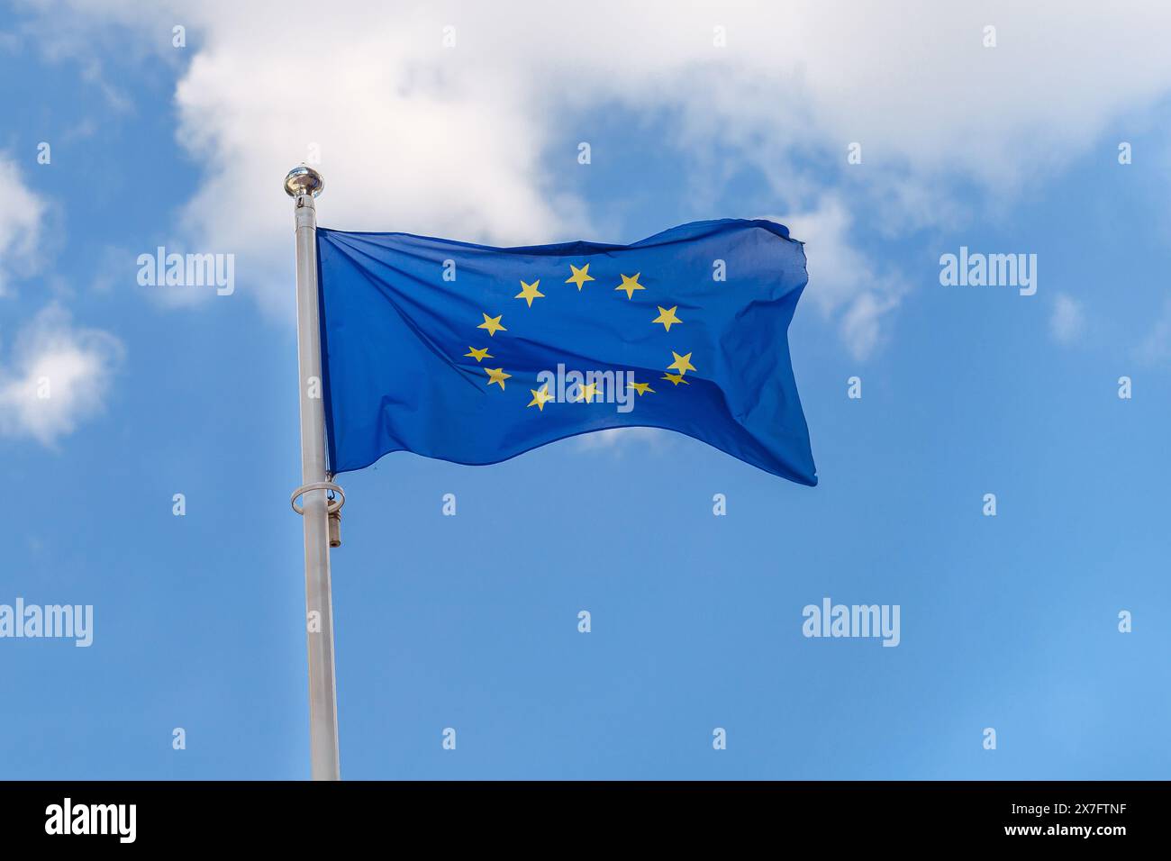 Close-up the flag of the EU, European Union flies against the background of a cloudy blue sky Stock Photo