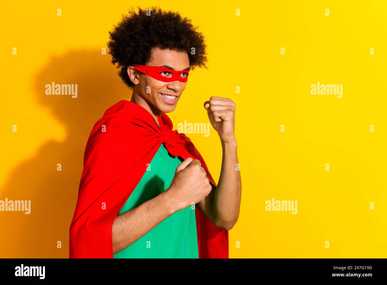 Portrait of funny super hero costume young man fight empty space isolated on yellow color background Stock Photo