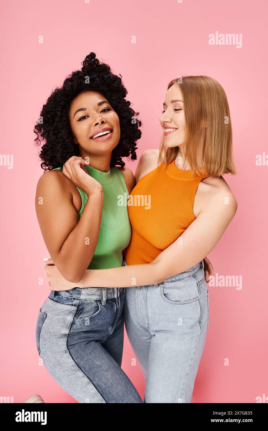 Two women, diverse and stylish, share a warm hug against a soft pink ...