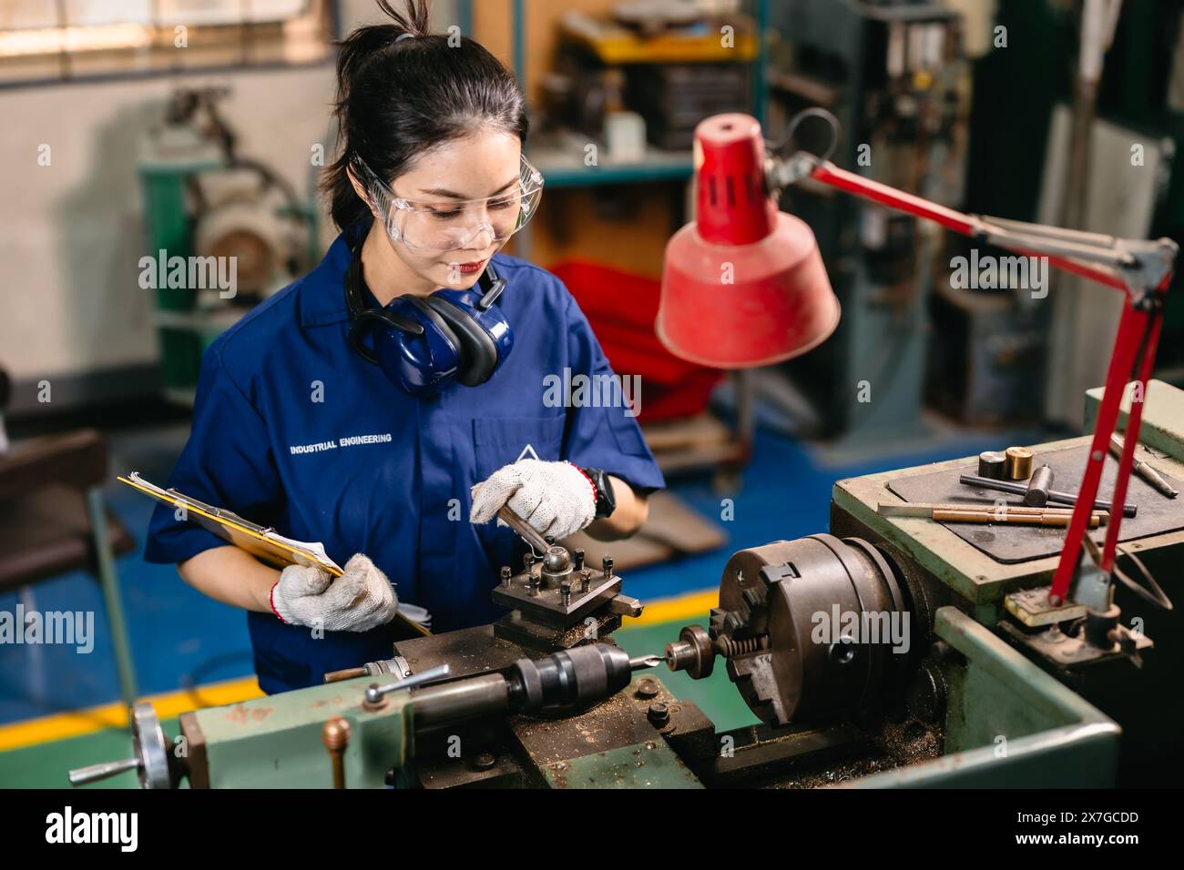 professional engineer worker with safety eyes protection focus working in metal lathe milling machine heavy industry factory. Stock Photo