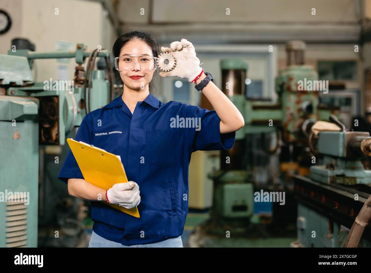 Portrait happy engineer worker with safety eyes protection glasses professional working with metal lathe milling machine heavy industry factory. Stock Photo