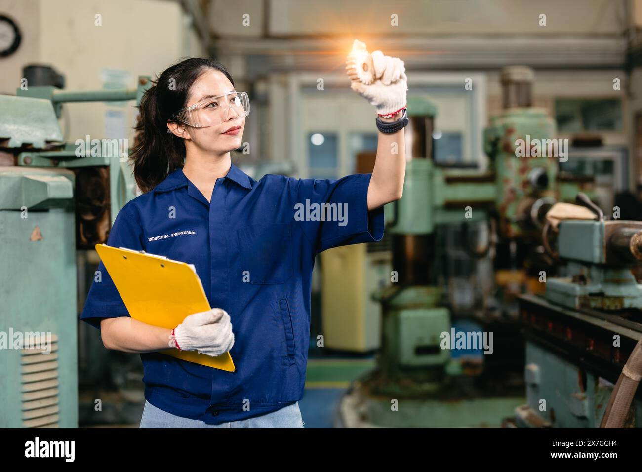 professional engineer worker with safety eyes protection focus working in metal lathe milling machine heavy industry factory. Stock Photo