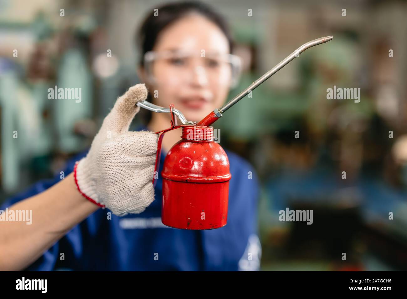 worker hand holding long neck oil lubricant can lube container for machine heavy industry workshop Stock Photo