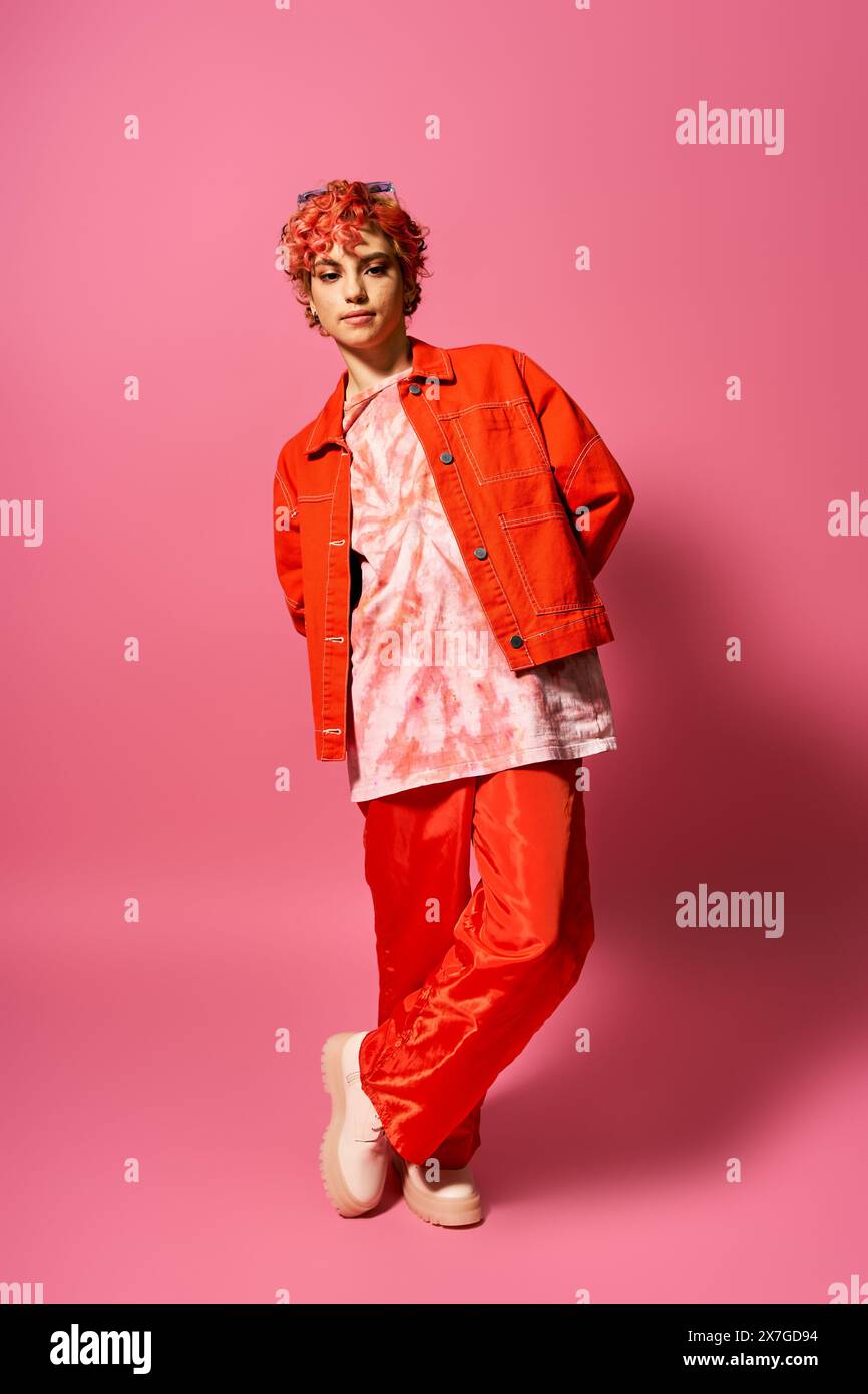 Young woman stands out in colorful attire of orange jacket and red pants. Stock Photo