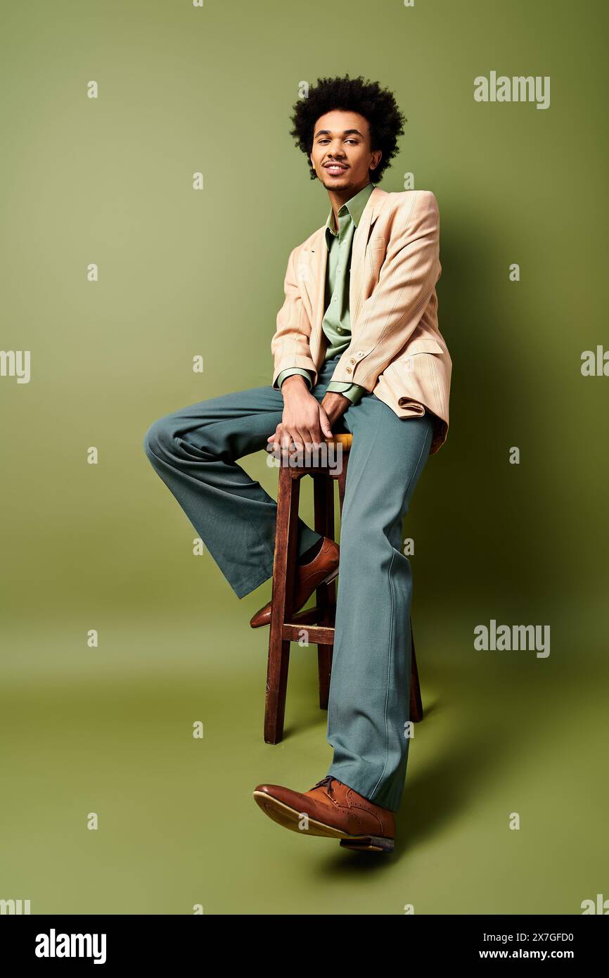 A stylish young African American man with curly hair sits confidently ...