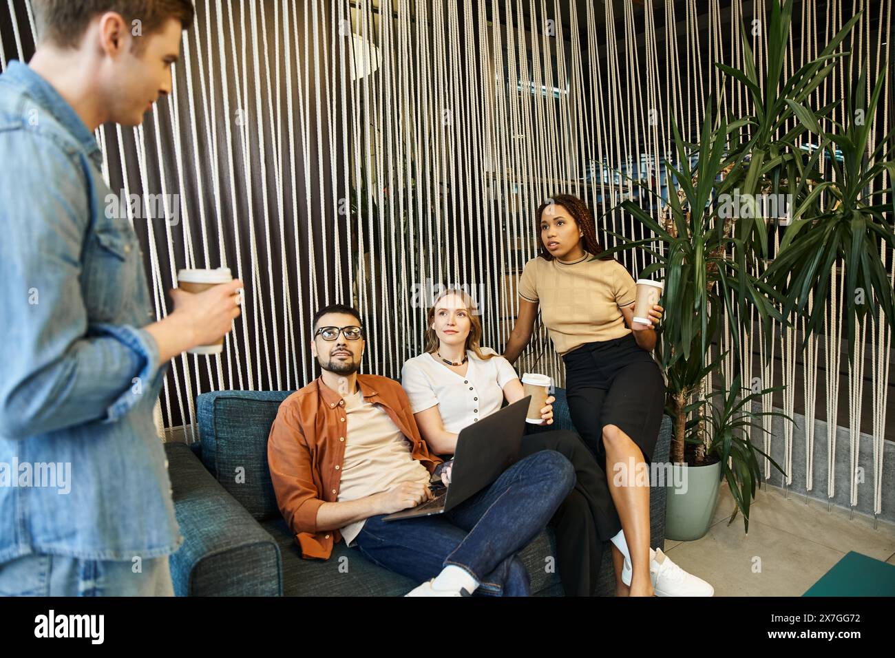 A diverse group of colleagues sitting on a couch in a modern room ...