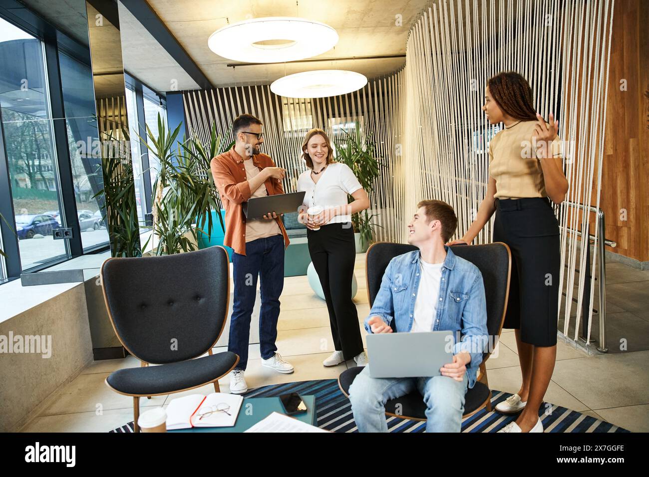 A diverse group of colleagues are gathered around a laptop, engaged in ...