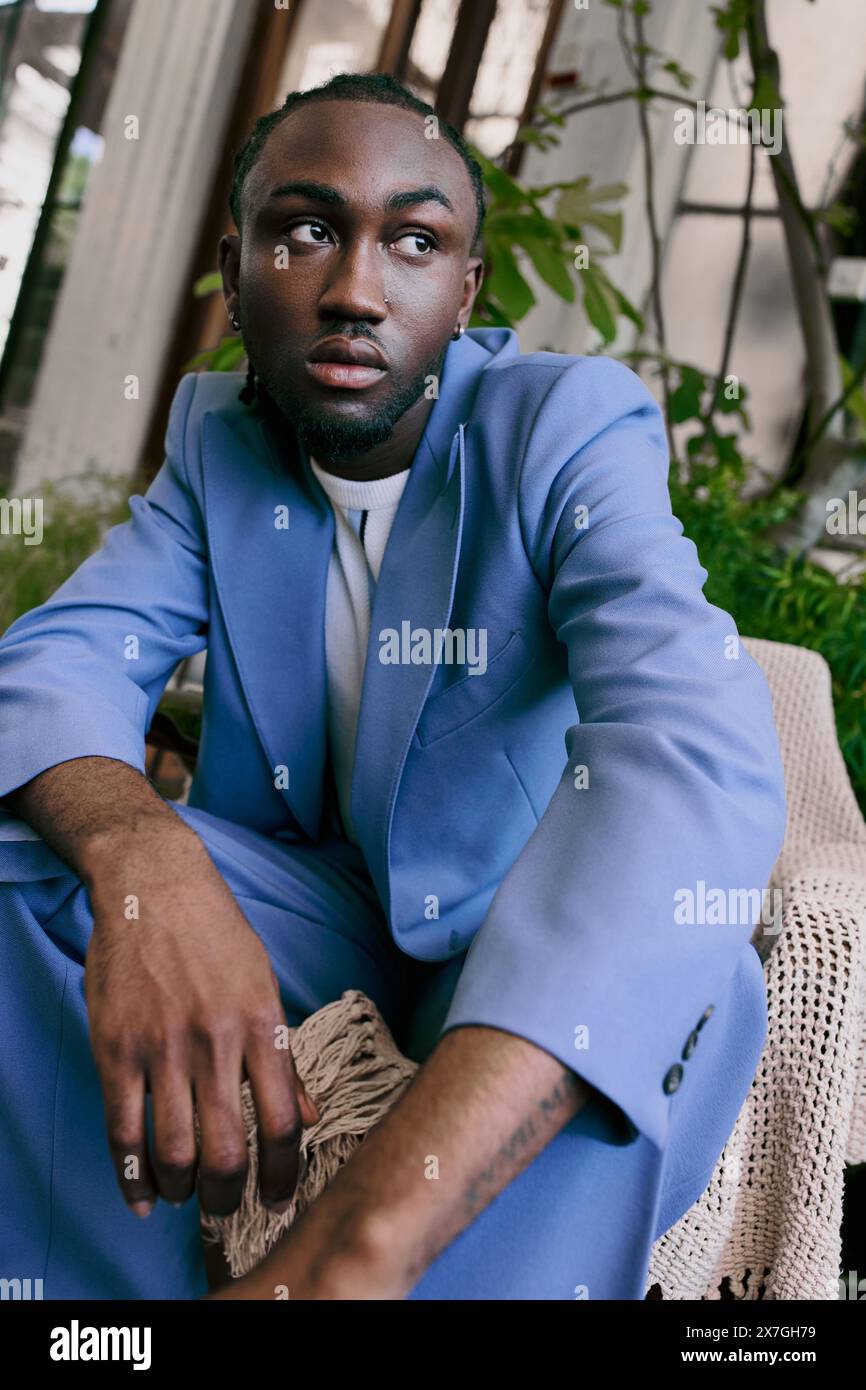 Stylish African American man in blue suit sitting on a chair in a ...