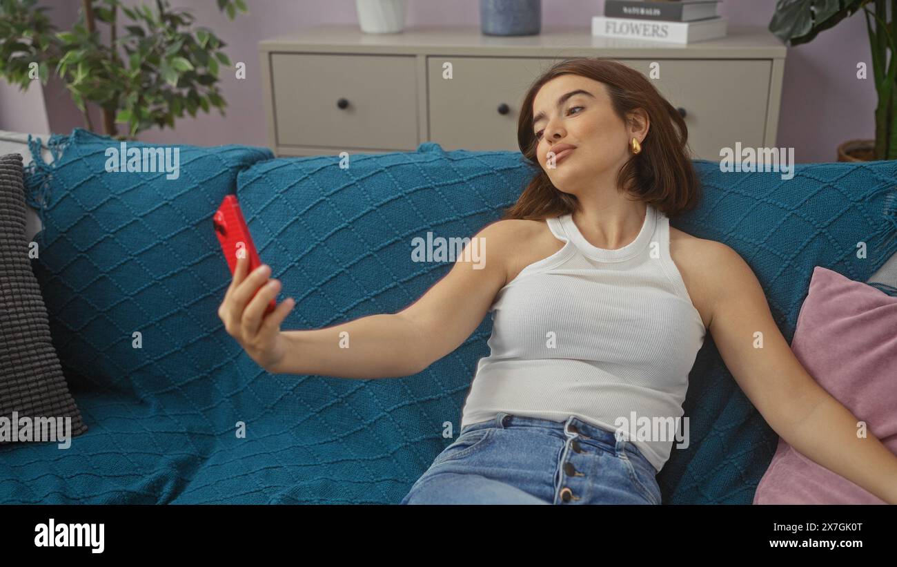 A young hispanic brunette woman takes a selfie at home in the living ...