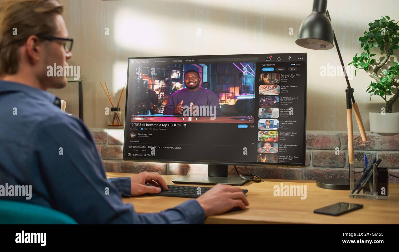 Handsome Man Watching Video Sharing Service Mock-up Where African American Influencer Talks About Lifestyle. Celebrity Blogger Having fun. Interface with Related Streams, Likes, Comments. Stock Photo