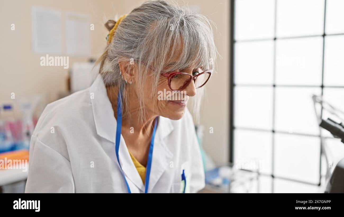 A mature hispanic woman with grey hair wearing glasses and a lab coat ...