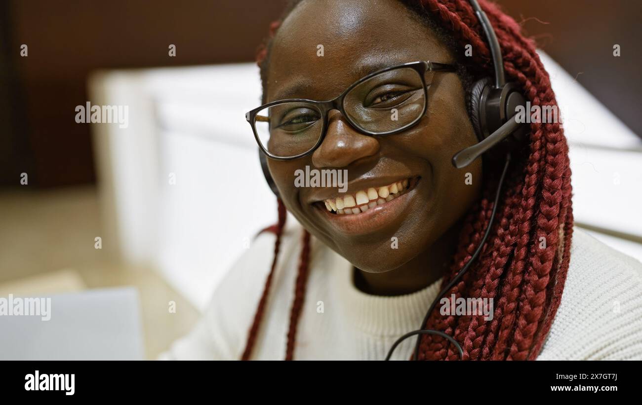 A cheerful african american woman with braids wearing glasses and a ...