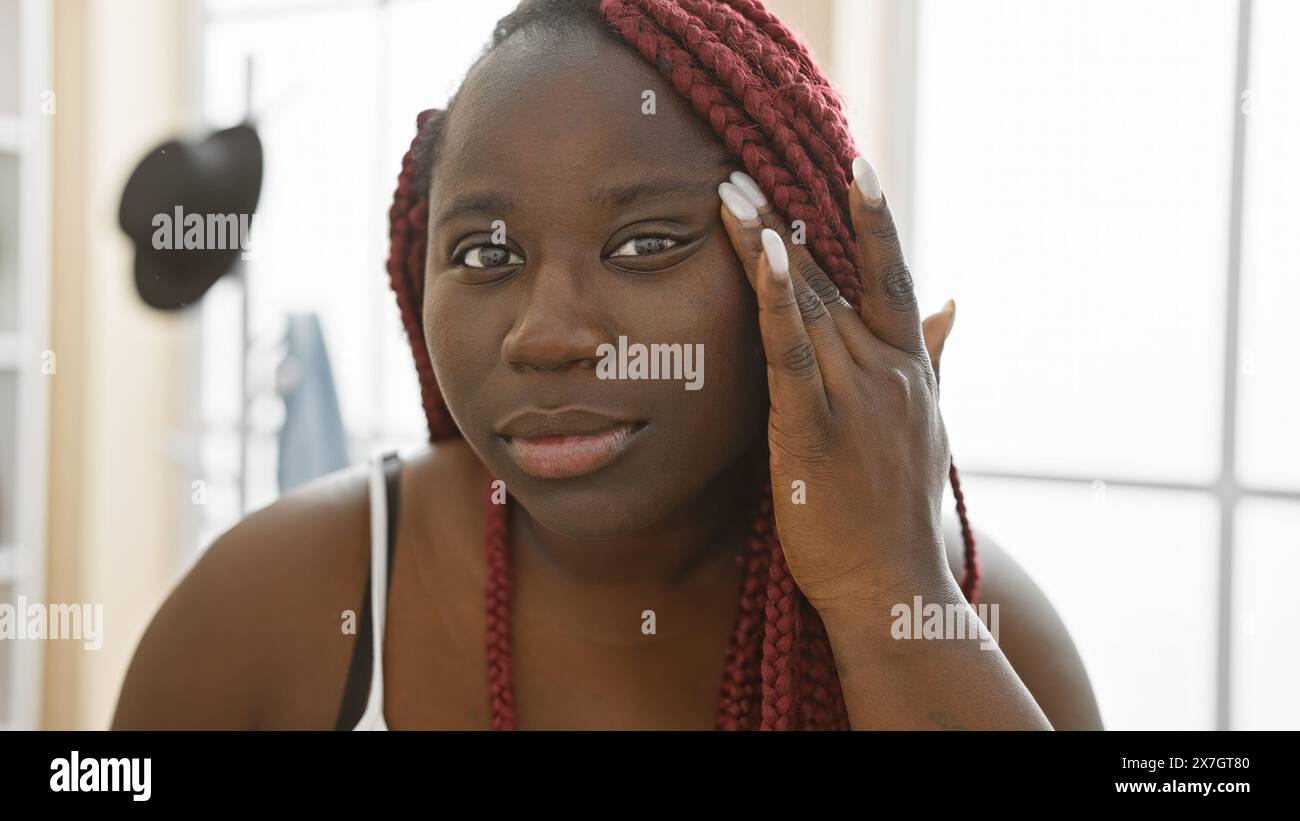 A beautiful african woman with braids poses thoughtfully in an indoor ...