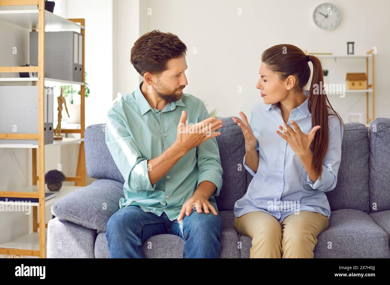 Young couple sitting at home and arguing in the living room. Quarrel and divorce concept. Stock Photo