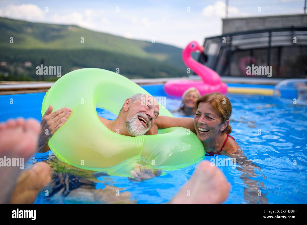 Senior Pool Fun Group of cheerful seniors shaving fun in pool jumping, swiming and ...
