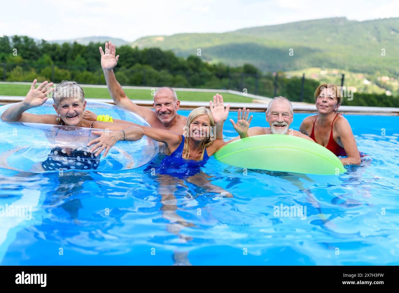 Senior Pool Fun Group of cheerful seniors shaving fun in pool jumping, swiming and ...