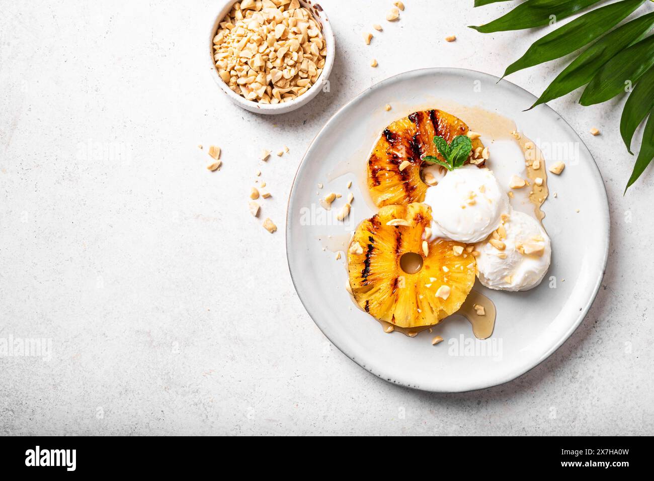 Grilled pineapples with rum glaze, vanilla icecream and grated peanuts, tropical dessert. Vegan