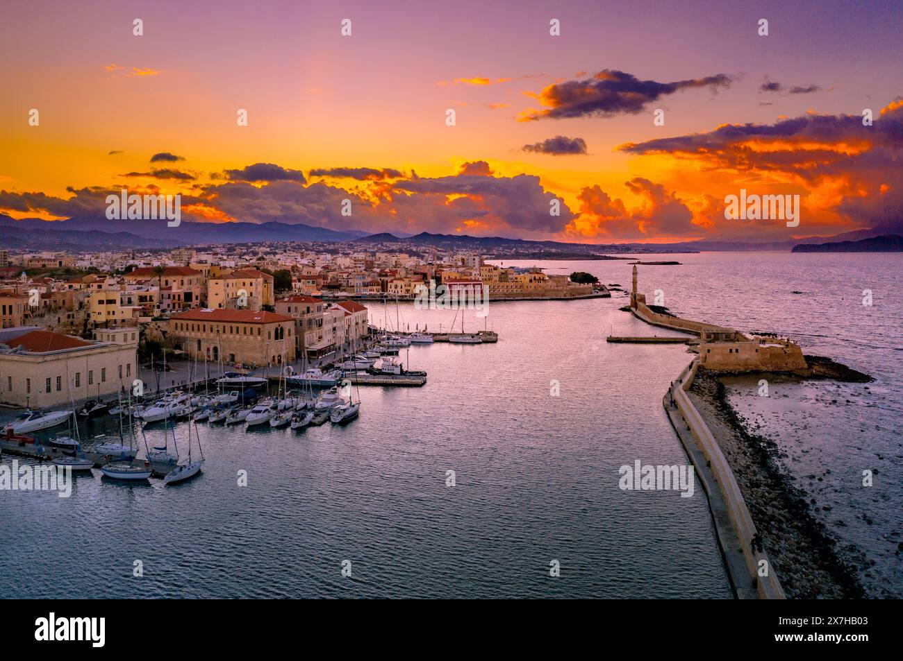 Panorama of the beautiful old harbor of Chania with the amazing lighthouse, mosque, venetian shipyards, at sunset, Crete, Greece. Stock Photo