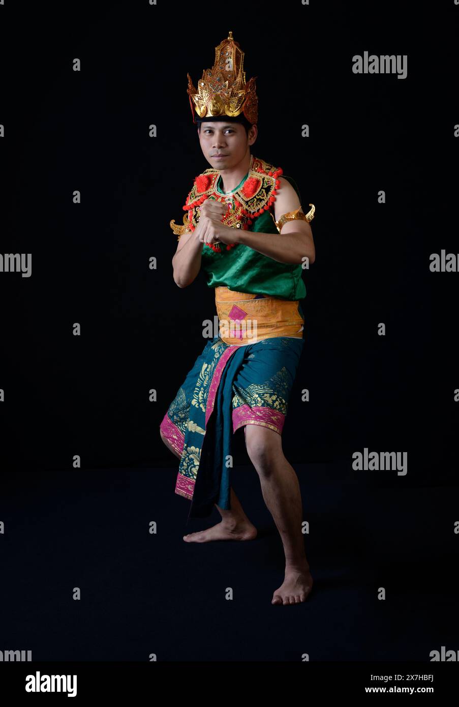 Indonesian man performing a traditional warrior dance in ornate, colorful attire Stock Photo