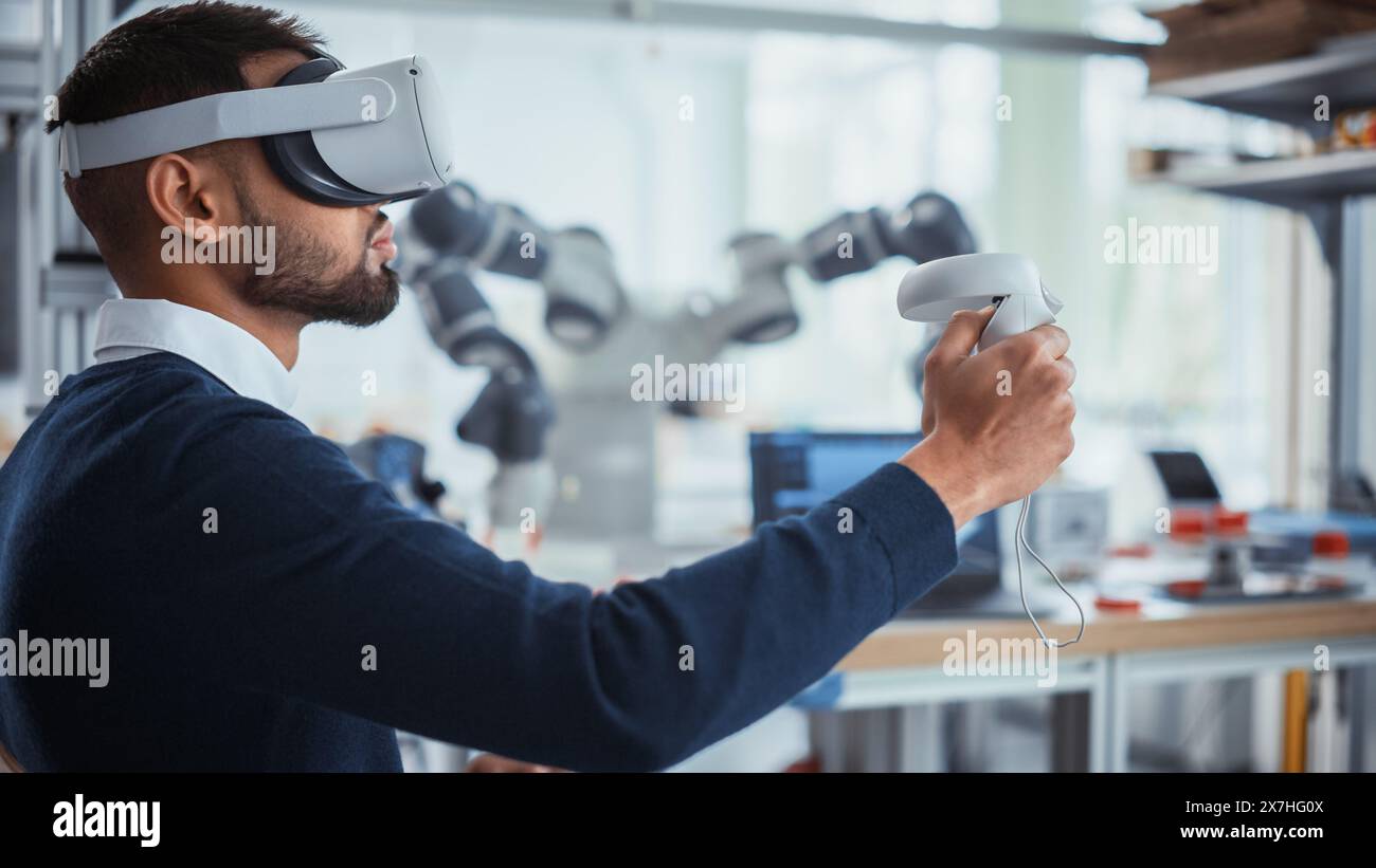 Computer Science Worker in Virtual Reality Headset Holding Controllers and Moving Bionic Claw. Man Developing Program for Motion of Robotic Arm. Innovative Automation Technologies Concept. Stock Photo