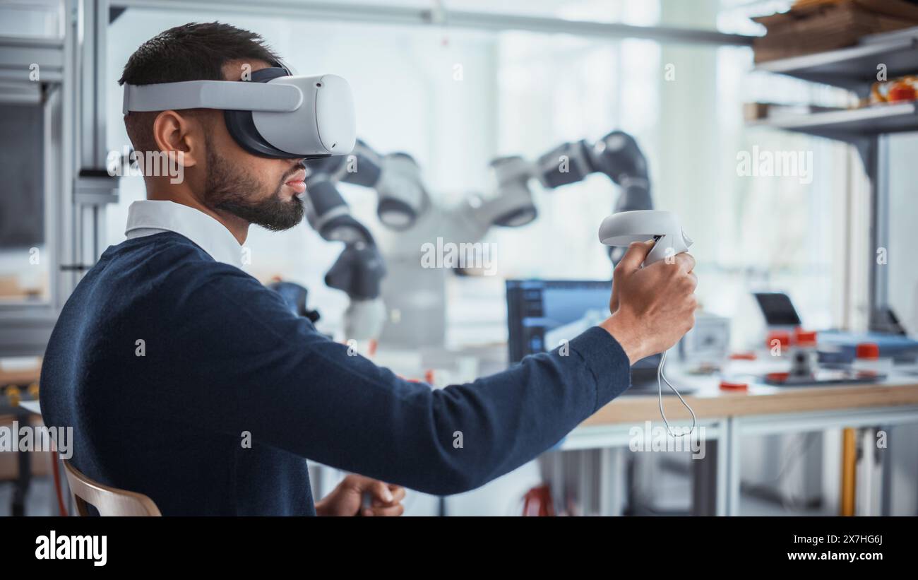 Computer Science Worker in Virtual Reality Headset Holding Controllers and Moving Bionic Claw. Man Developing Program for Motion of Robotic Arm. Innovative Technologies for Automation Concept. Stock Photo