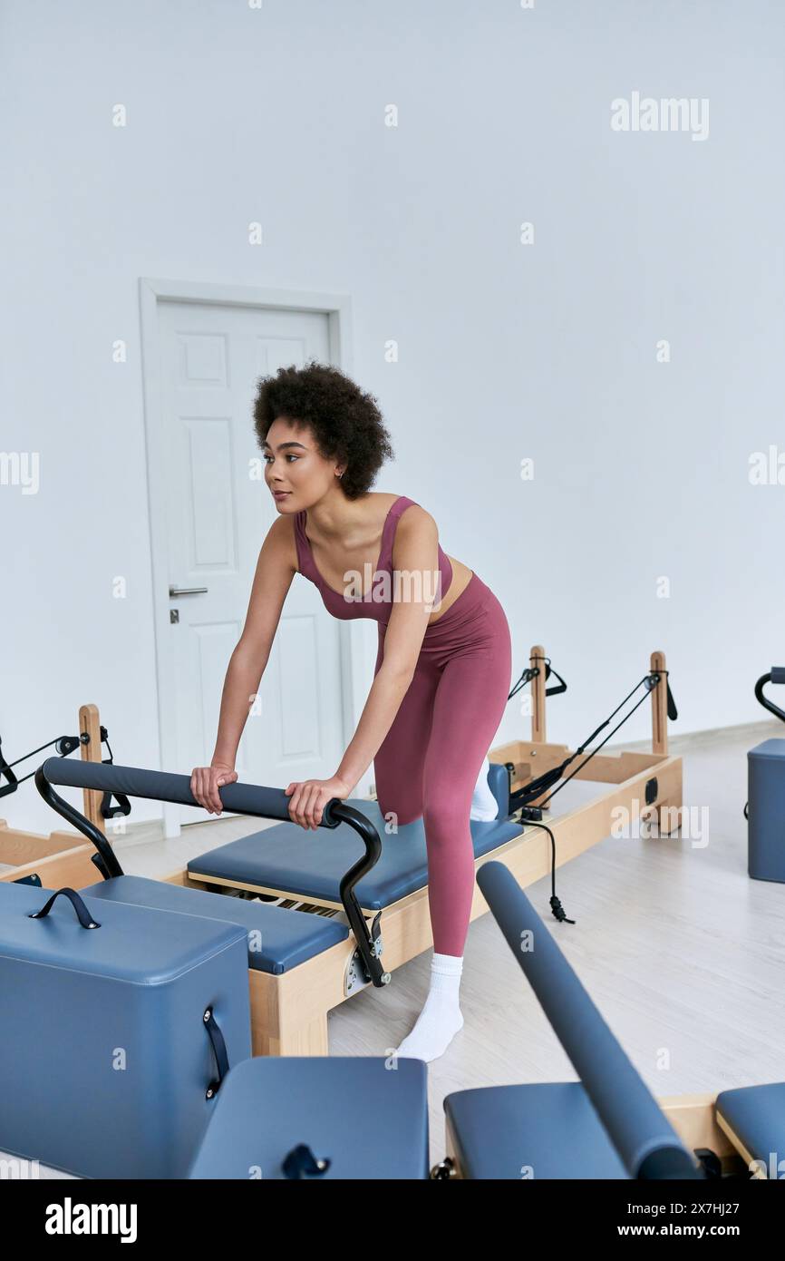 A woman gracefully performs pivots on a rowing machine. Stock Photo