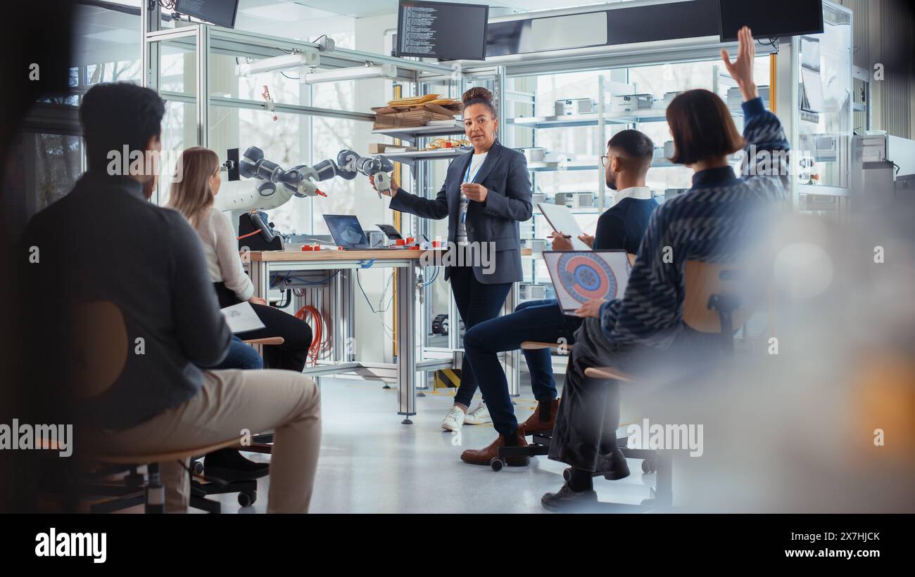 Office Conference Room Meeting: Black Female Developer Doing Robotics Industry Presentation to a Diverse Multi-Ethnic Team of Businesspeople, Explaining Robotic Arm Work Principles. Stock Photo
