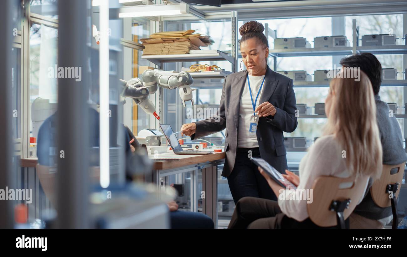 Team Meeting of Engineers Working on an Innovative More Efficient Ways of Robotic Arm Application. Group of Specialists Gathered Around Table, Solving Problems, Discussing Results. Stock Photo