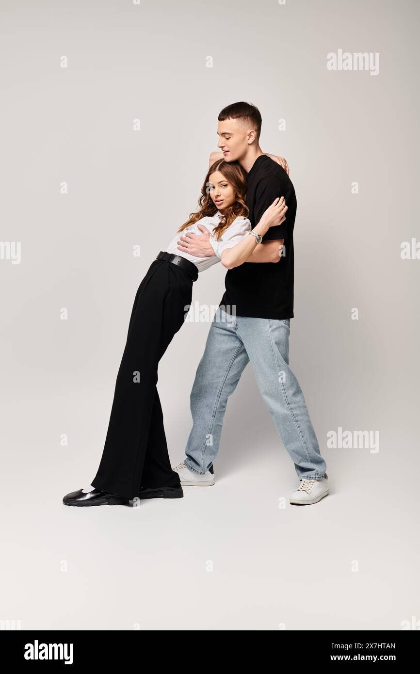 A young couple in love dancing gracefully in a studio with a grey background. Stock Photo