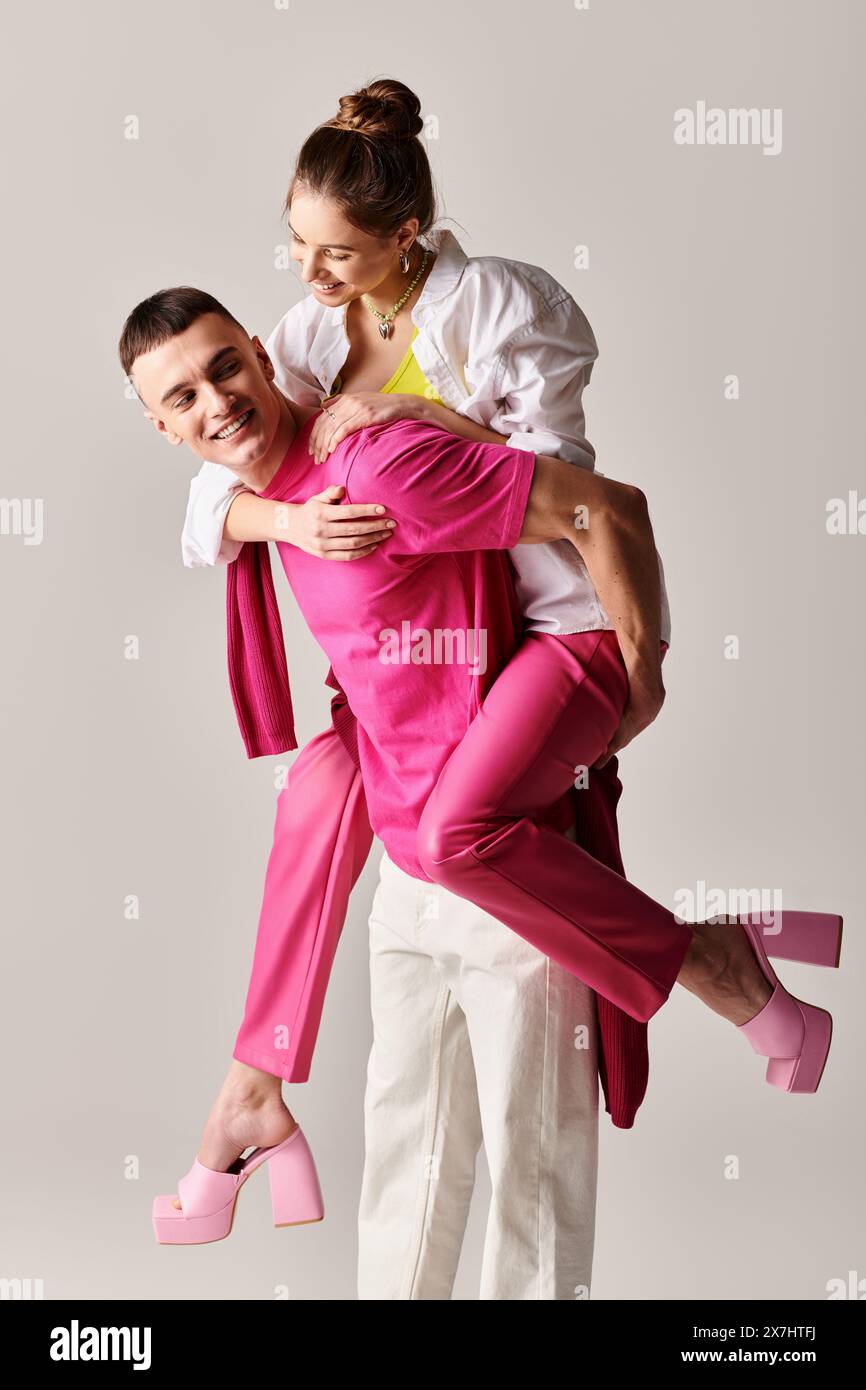 A stylish young man tenderly holds a woman in his arms against a grey studio background. Stock Photo