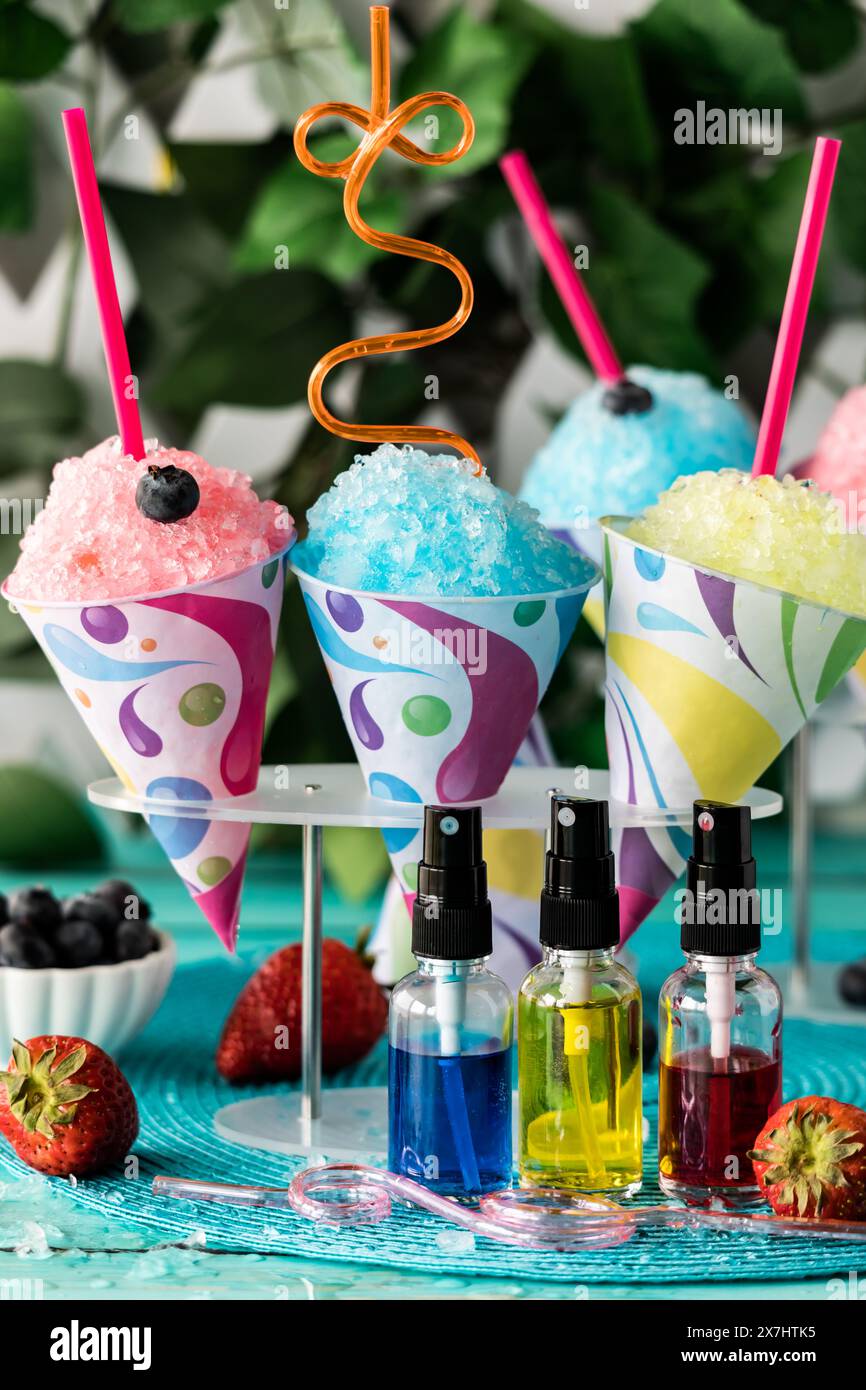 Colourful homemade snow cones with fruit flavoured syrups in front