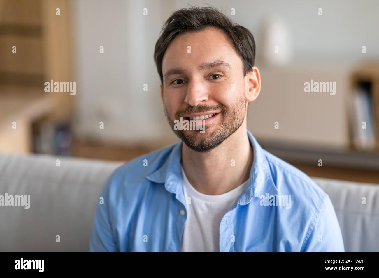 Handsome Bearded Man Smiling on Couch at Home Stock Photo