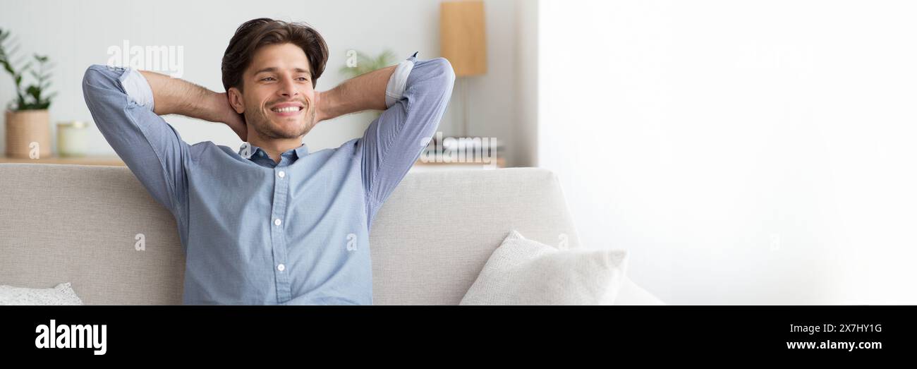 Relaxed young man sitting on couch at home Stock Photo