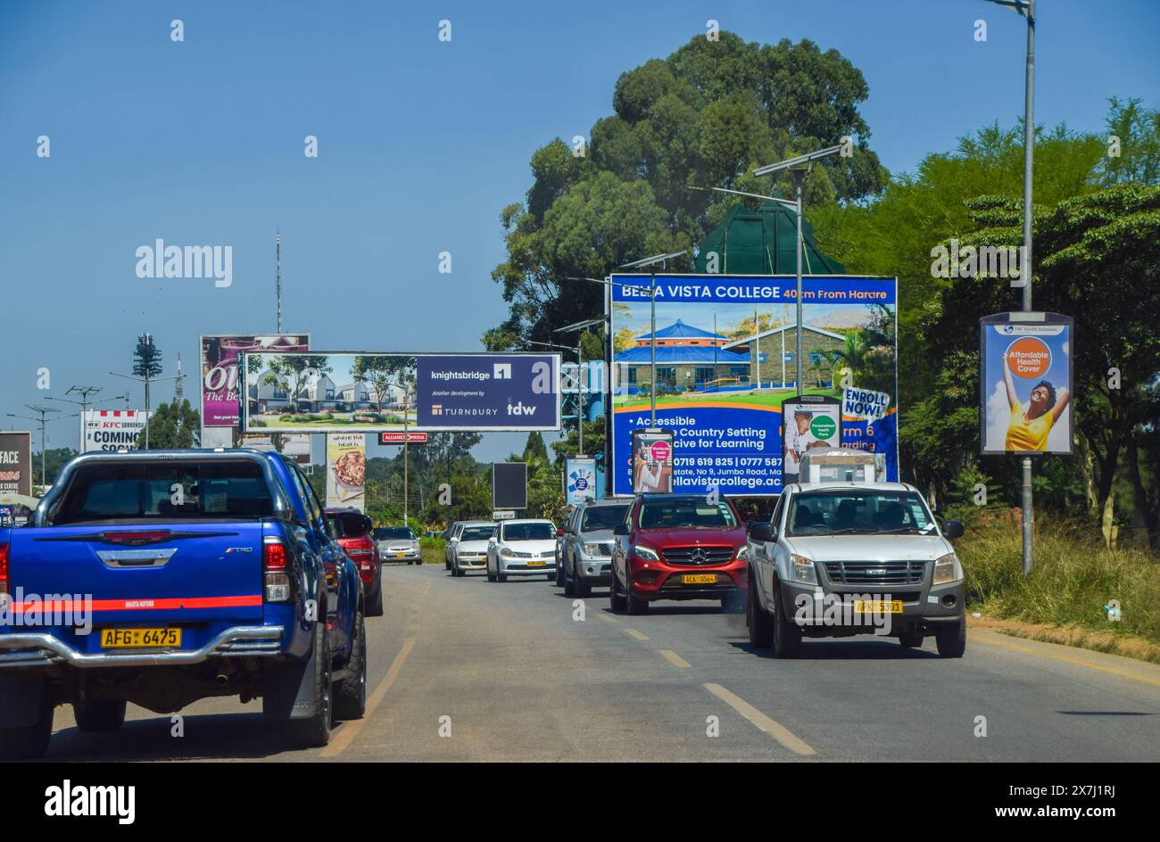 Harare, Zimbabwe. 20th April 2024: Advertising billboards and traffic on Borrowdale Road. Credit: Vuk Valcic/Alamy Stock Photo