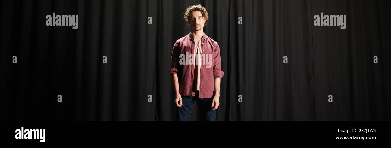 A man standing confidently in front of a black curtain. Stock Photo