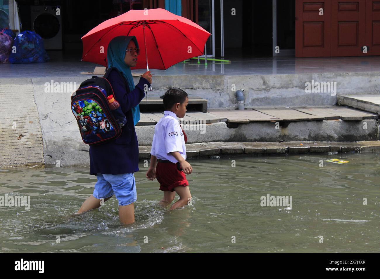 Medan Selayangh, North Sumatra, Indonesia. 20th May, 2024. A mother helps her child get home from school, through flash floods that hit a number of coastal areas in Belawan City, North Sumatra, Indonesia (Credit Image: © Kartik Byma/ZUMA Press Wire) EDITORIAL USAGE ONLY! Not for Commercial USAGE! Credit: ZUMA Press, Inc./Alamy Live News Stock Photo