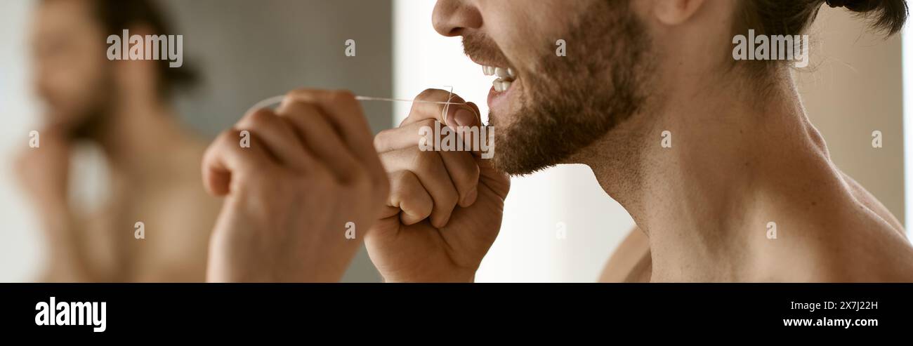 A man diligently brushes his teeth in front of a mirror. Stock Photo