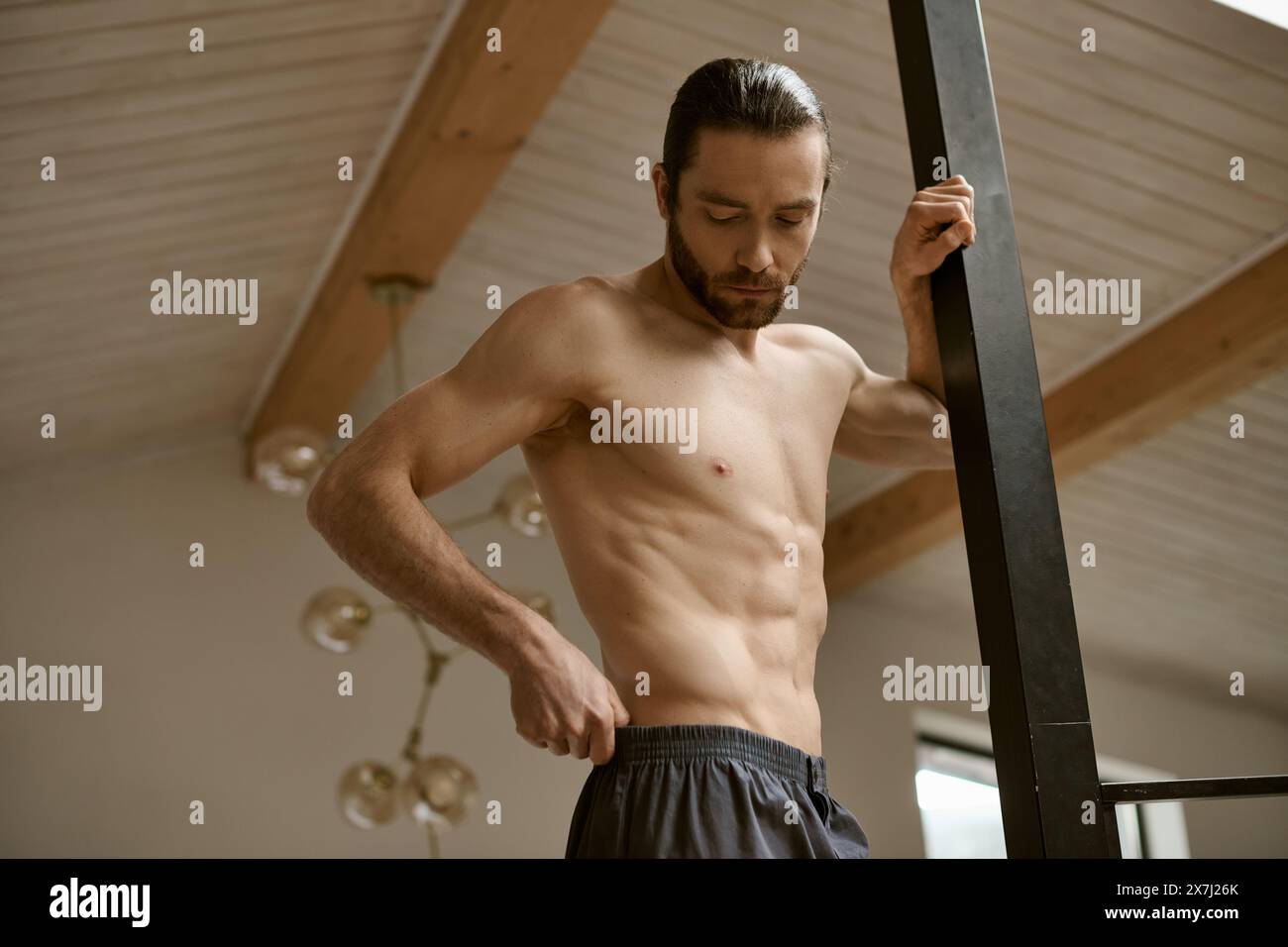 Shirtless man tones muscles at home. Stock Photo