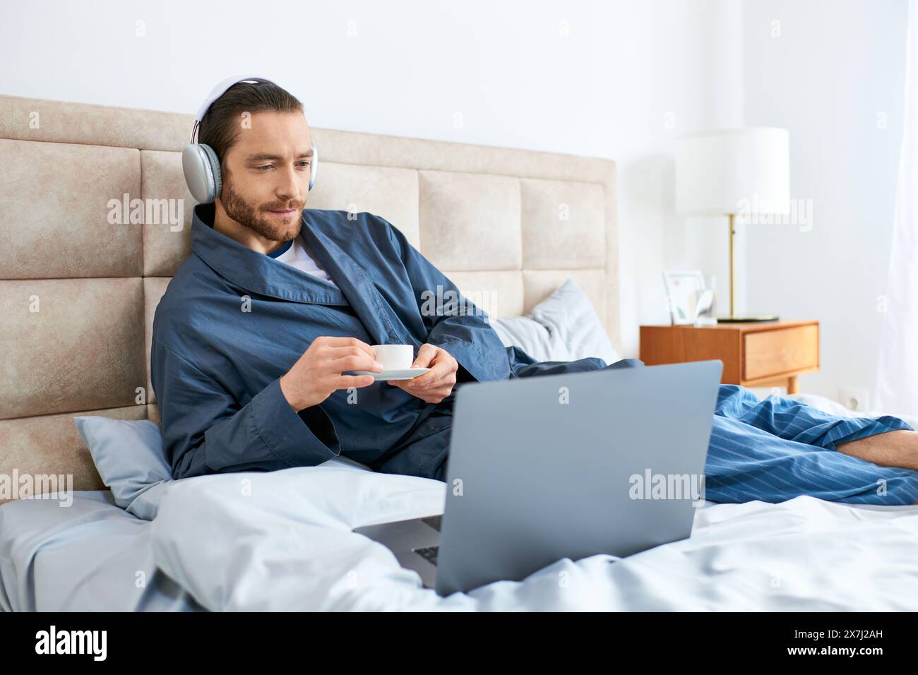 A man in relaxation pose on bed, using a laptop. Stock Photo