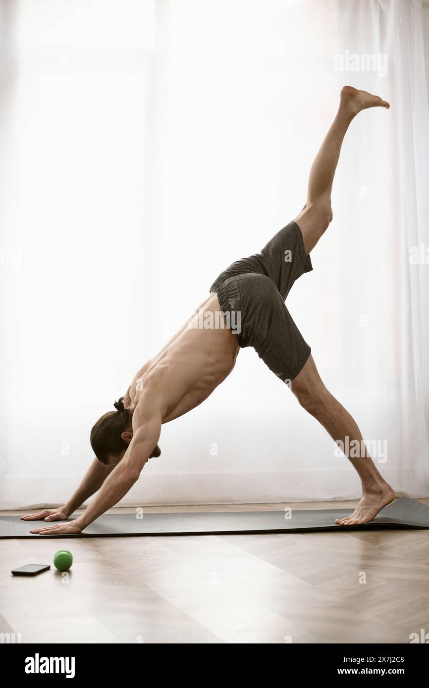 Handsome man in a yoga pose by a window at home. Stock Photo