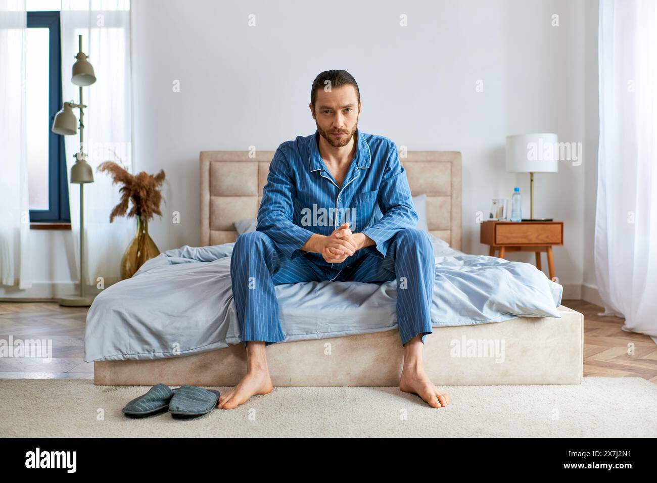 Handsome man in pajamas on top of a bed. Stock Photo