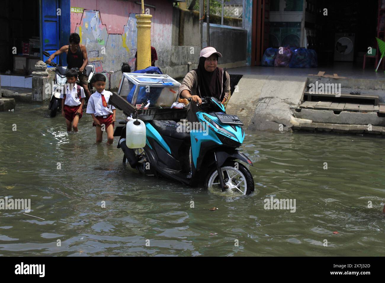 Medan Selayangh, North Sumatra, Indonesia. 20th May, 2024. A woman pushing a motorbike, after it broke down because it was submerged in a flash flood that occurred due to overflowing sea water, in Bagan, Belawan City. The Meteorology, Climatology and Geophysics Agency estimates that there will be additional flooding as high as 2.7 meters in the Belawan Coastal Area, North Sumatra (Credit Image: © Kartik Byma/ZUMA Press Wire) EDITORIAL USAGE ONLY! Not for Commercial USAGE! Credit: ZUMA Press, Inc./Alamy Live News Stock Photo