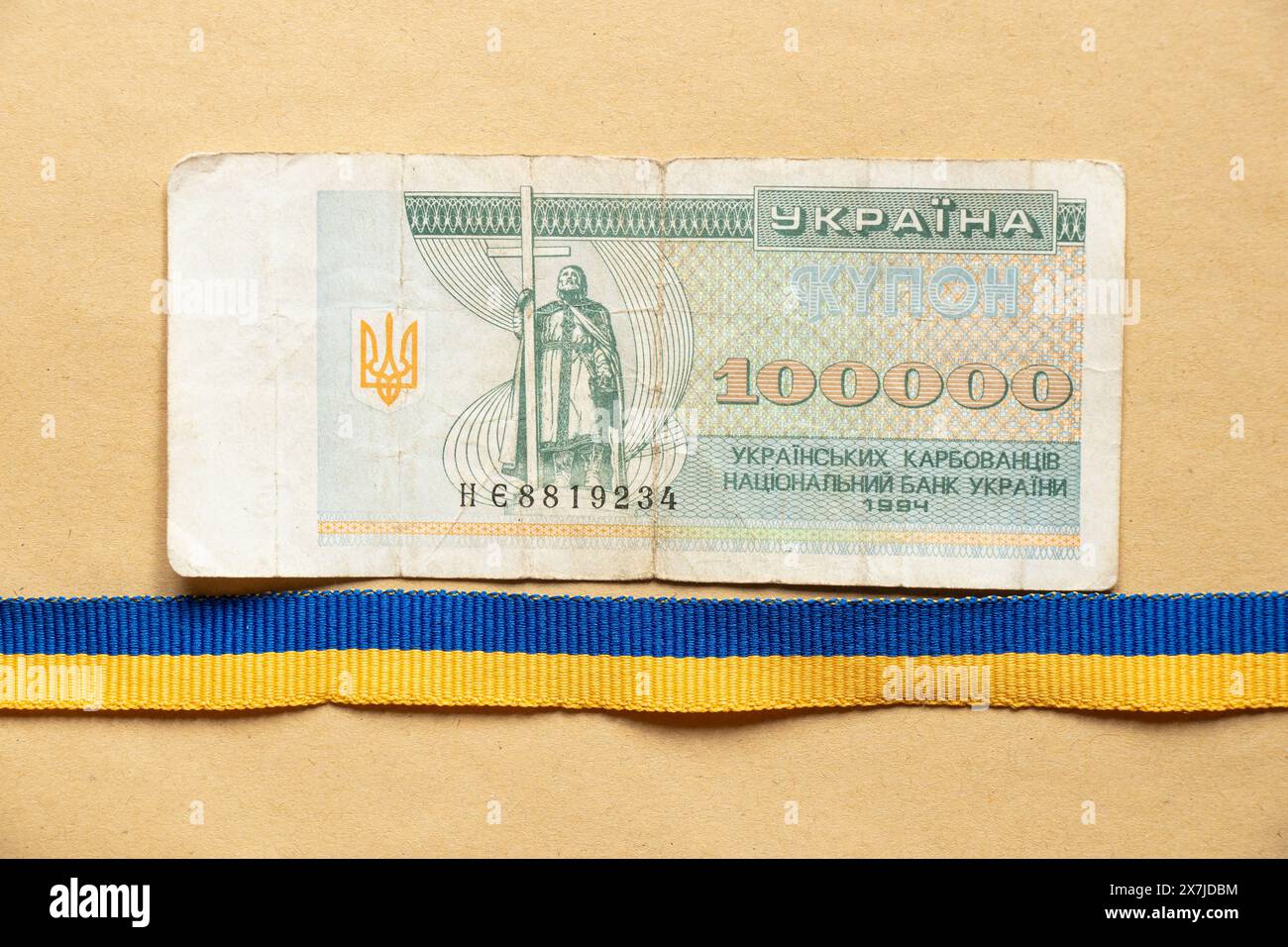 One hundred thousand Ukrainian Carbonates and a ribbon of the Ukrainian flag blue on brown paper, the money of Ukraine Stock Photo
