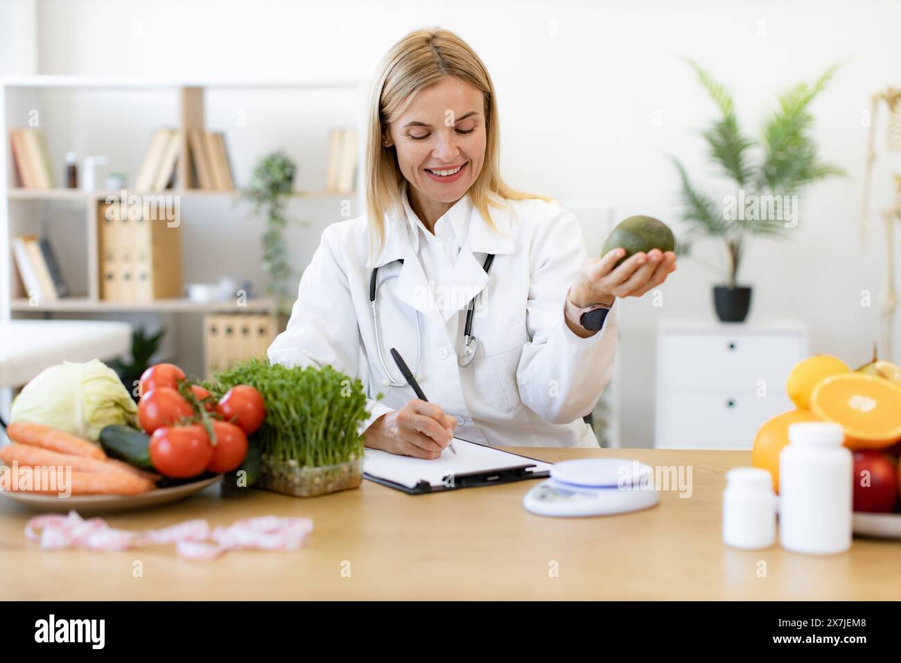 Happy female writing prescription for patients proper healthy diet. Mature Caucasian female nutritionist making healthy eating plan and calculating ca Stock Photo