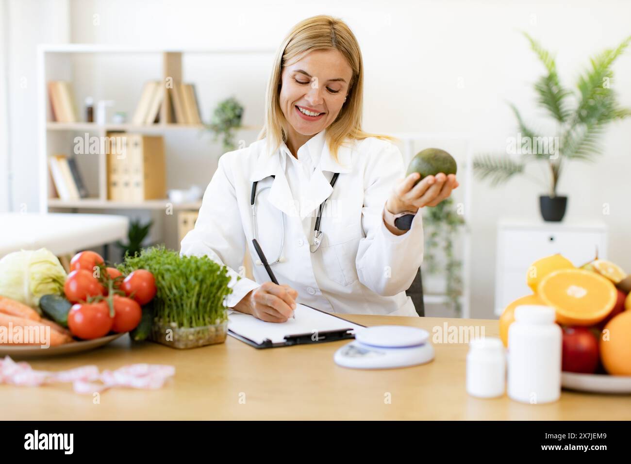 Happy female writing prescription for patients proper healthy diet. Mature Caucasian female nutritionist making healthy eating plan and calculating ca Stock Photo