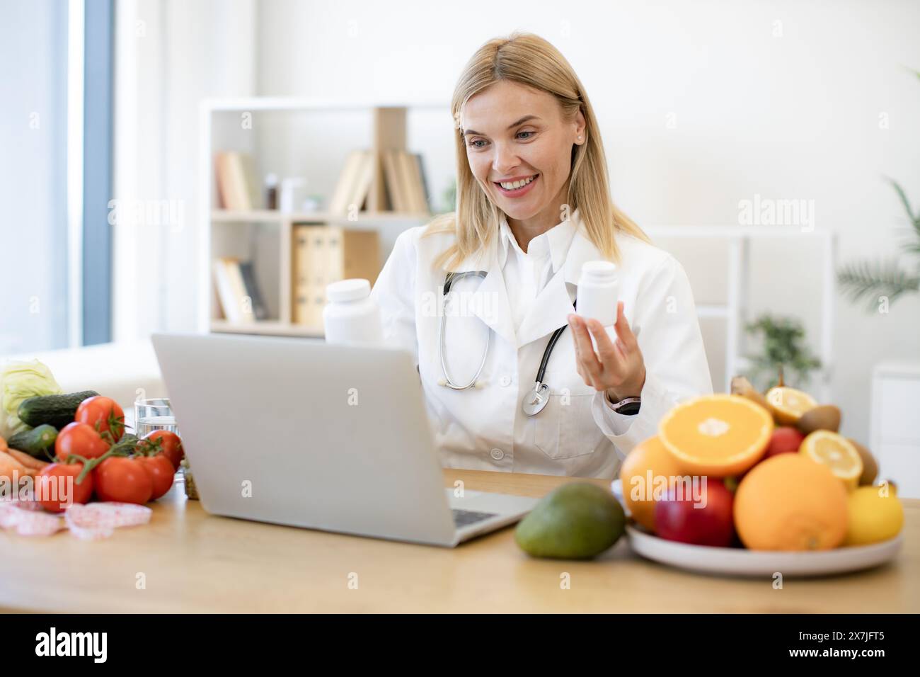 Mature nutritionist female doctor explaining medical treatment to the patient through a video conference using laptop. Telehealth and telemedicine con Stock Photo